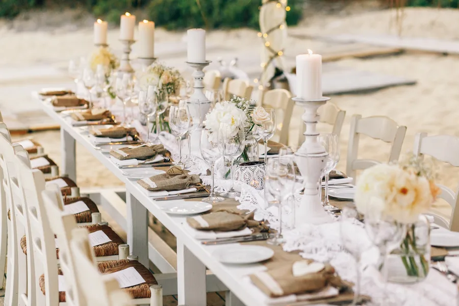 A long table set with pale linen, tapers and low bowls of flowers